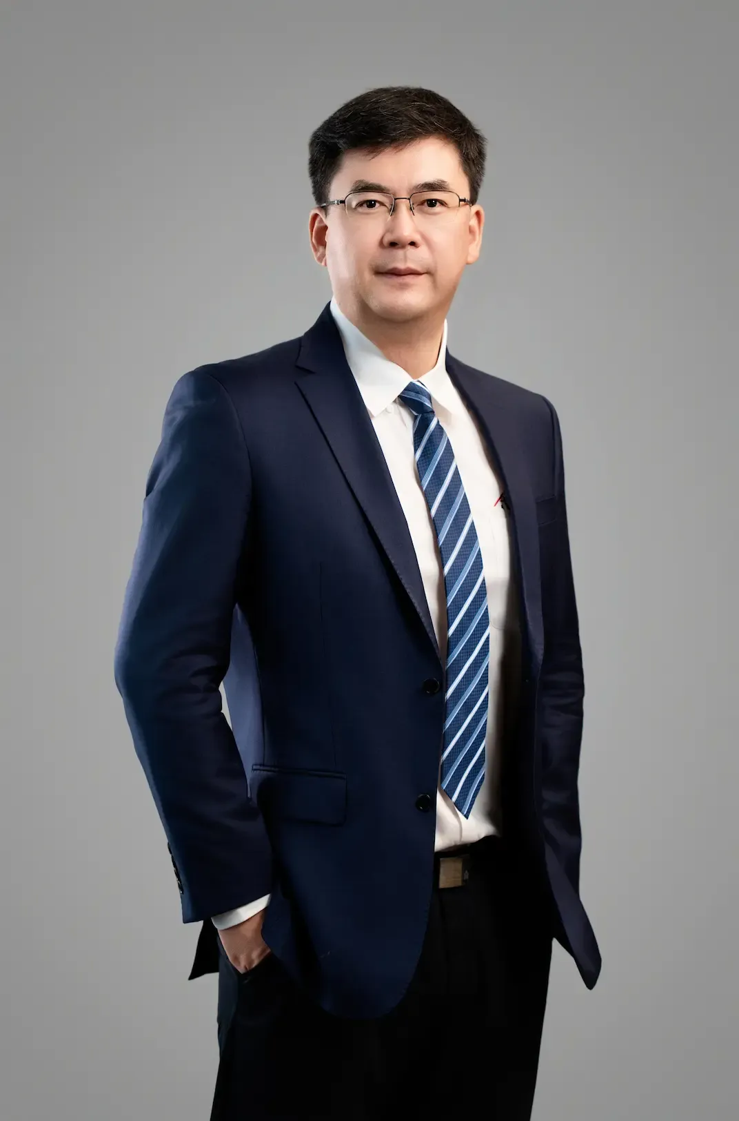 一位身穿深蓝色西装、戴着眼镜的职场人士，神态自信地站着。