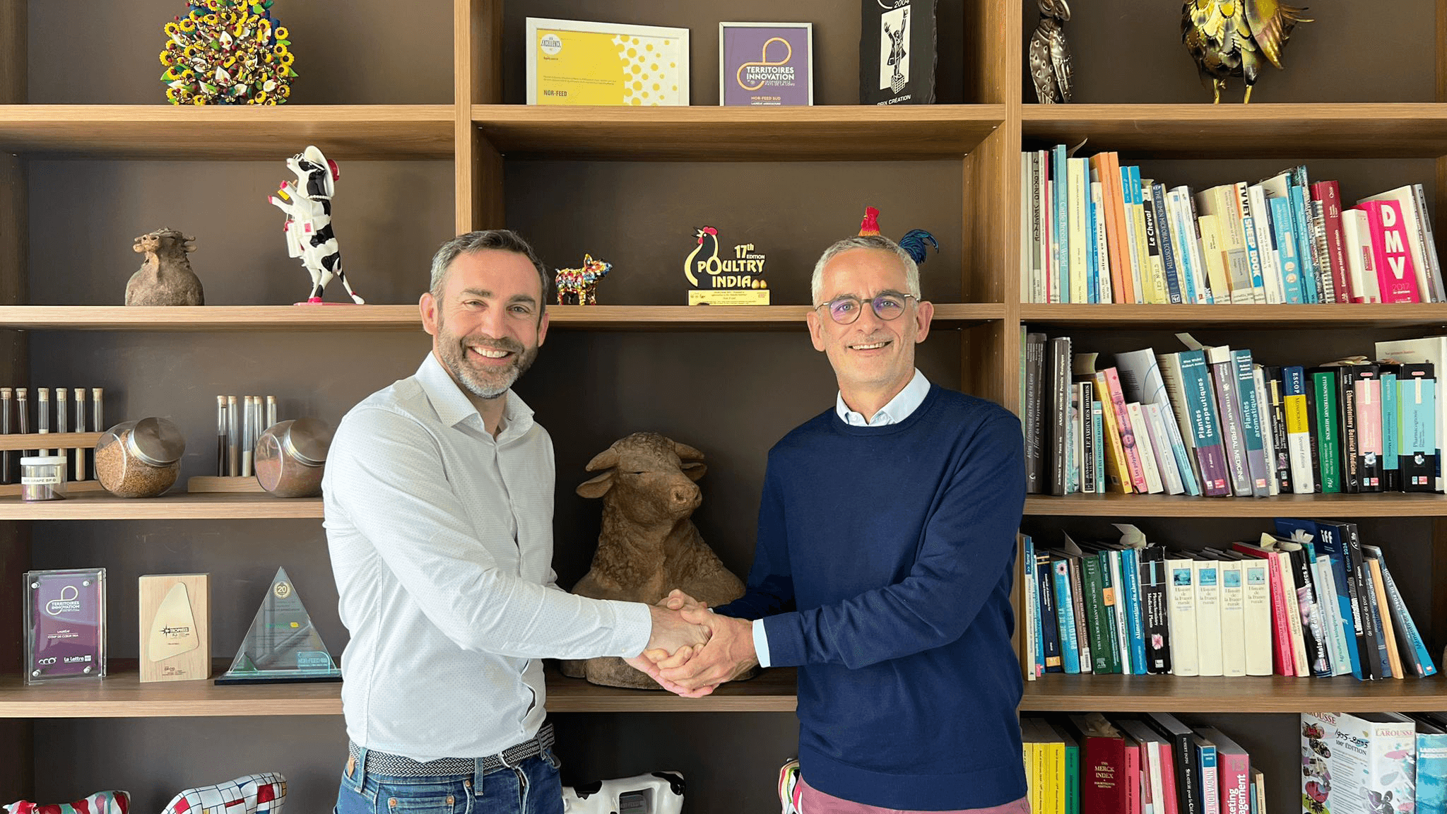 两名男子在办公室里握手，周围是书架和装饰品。