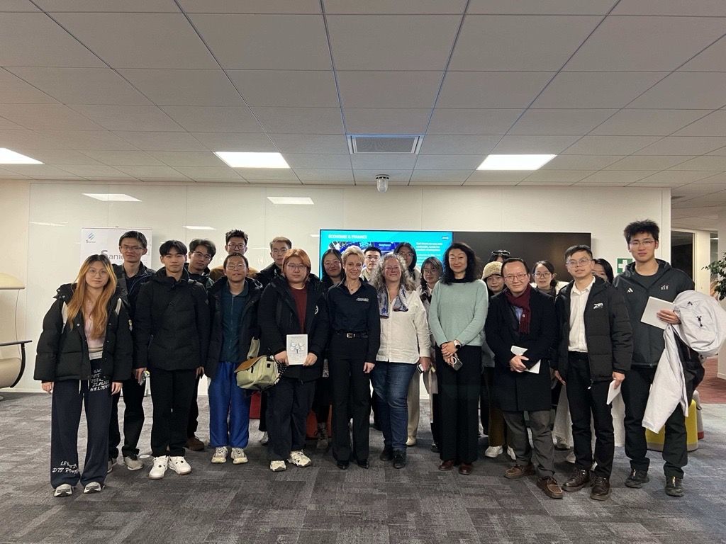 Un groupe diversifié de jeunes adultes debout et souriants dans un bureau moderne.